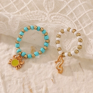Handmade beaded ring set featuring golden crab and seahorse charms with colored beads