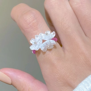 Macro view of handmade beaded ring featuring white acrylic flowers and pink beads