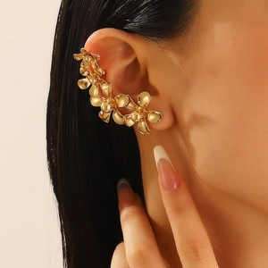 Primer plano de un ear cuff vintage dorado con elegantes pétalos de flores de metal en oreja