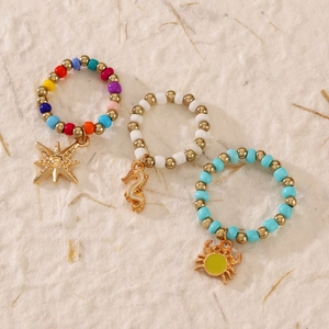 Handmade beaded ring set featuring colorful stars, seahorse and crab gold pendants