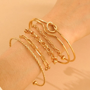 Detail of five-piece gold bracelet set featuring knot designs and textured chain links