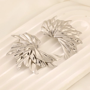 Modern silver spiral leaf earrings with a polished mirror finish on a stone tray