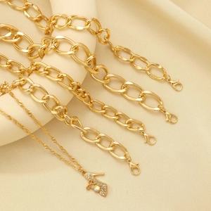Close-up of golden geometric knotted bracelets and stiletto heel pendant with crystals