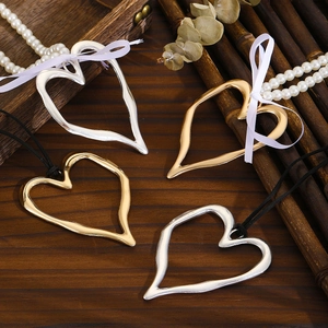 Detail view of gold and silver heart pendants on pearl beaded chains and black leather cords