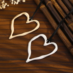 Macro view of gold and silver liquid metal heart pendants on a rustic wood background