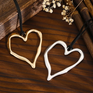 Detailed macro view of heart pendants with irregular lava texture on dark wood background