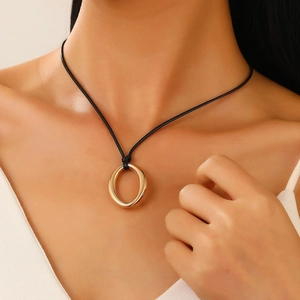 Close-up of a minimalist golden heart pendant on a black cord necklace worn by a model