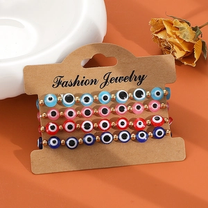 Set mit vier bunten Evil-Eye-Perlenarmbändern mit Goldakzenten auf einer Karte