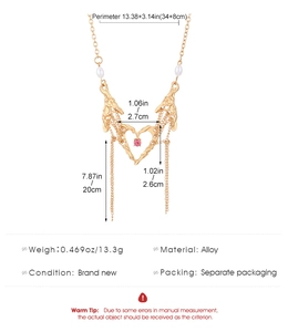 Nahaufnahme von goldenem Herzanhänger mit Skeletthänden und rosa Edelsteindetails