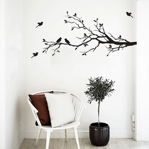 Minimalist black wall sticker featuring bird silhouettes on a leafy branch in a cozy room