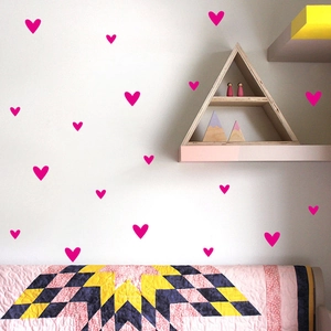 Pink heart-shaped wall stickers in a cozy Nordic style nursery with wooden furniture decor