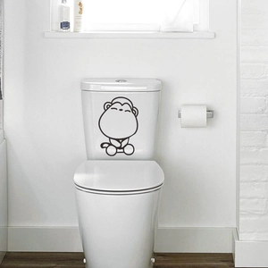 Cartoon monkey wall sticker for bathroom decor on a white toilet lid in modern setting