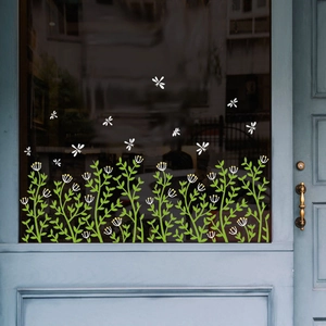 Detail of green grass and white dragonfly decals applied to glass window surface