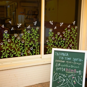 Detail showing green flower wall stickers and dragonflies on a cafe glass window display