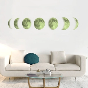 Detailed view of seven glowing moon phase wall stickers above a modern white sofa