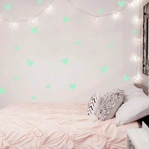 Luminous green heart wall stickers glowing above a pink bed in a cozy bedroom setting