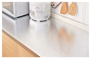 Close-up of silver embossed aluminum kitchen foil sticker on a wooden countertop