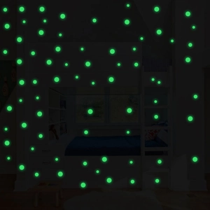 Detailed view of luminous green circular wall stickers glowing in a dark bedroom