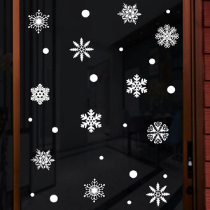 Detailed view of assorted white snowflake static stickers on a dark glass window surface