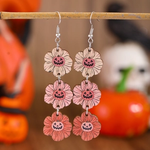 Macro shot of layered wooden flower earrings with Jack-o'-lantern prints for Halloween