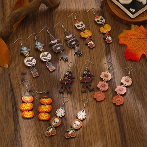 Macro shot of Halloween wooden earrings with pumpkin and ghost motifs on wood