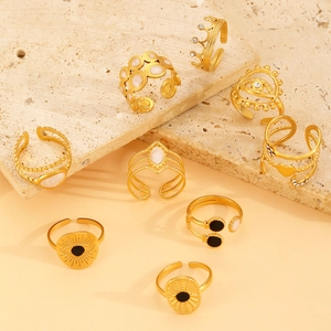 Macro view of gold hollow geometric and evil eye adjustable rings on stone