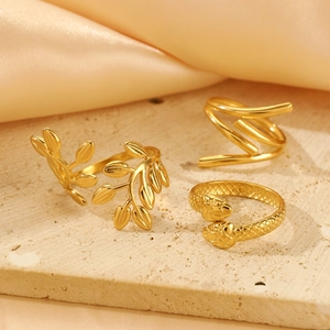 Detailed macro view of three gold rings with olive leaf and snake motifs on stone