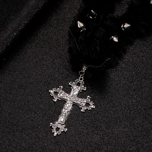 Dettaglio del ciondolo a croce gotica in argento con collana choker in pizzo e borchie