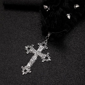 Dettaglio della croce gotica in argento con pizzo nero e borchie punk in metallo