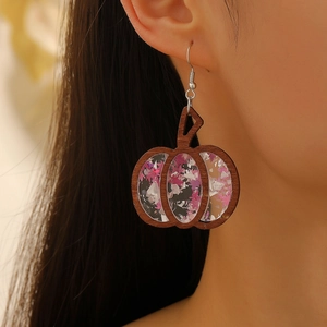 Close-up of wooden pumpkin earrings with purple glitter inlay on female model