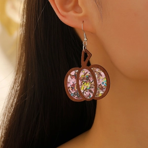 Detail of wooden pumpkin earrings featuring pink sequins and a western gothic style