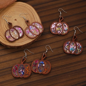 Detailed view of handmade wooden pumpkin earrings with colorful glitter resin fill