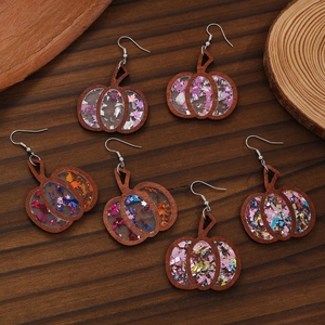 Detail of wooden pumpkin earrings with colorful glitter resin fill for Halloween