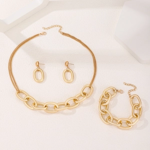 Detalle de un conjunto de joyas en oro mate con cadenas gruesas y pendientes