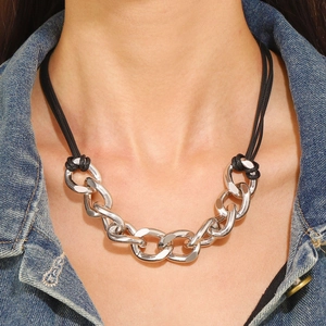 Primo piano della collana a catena d'argento spessa con cordino nero indossata dal modello