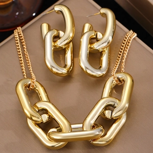 Detalle del conjunto de collar y pendientes de cadena gruesa dorada sobre cuero marrón
