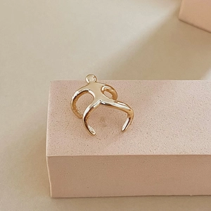 Detailed view of a gold-tone abstract human-shaped ear cuff with a high-polished mirror finish
