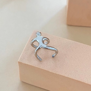 Macro shot of silver human-shaped ear cuff leaning on a geometric peach display block