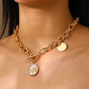Primo piano della collana dorata con fibbia OT e ciondolo albero della vita in madreperla