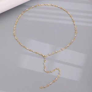 Detail einer vergoldeten Y-Kette mit hohlen Herzgliedern und weißen Kristallakzenten