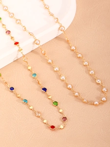 Detalle de collares en Y dorados elegantes con gemas multicolores y perlas blancas finas