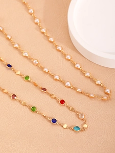 Detalle de collar con borlas doradas con gemas multicolores y elegantes perlas blancas