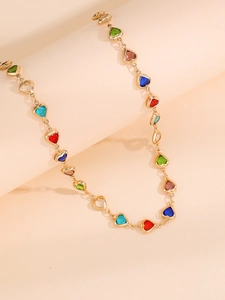 Detalle de collar en Y dorado con gemas de colores en forma de corazón y diseño calado