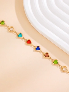Vista detallada de pulsera bañada en oro con gemas multicolores de corazón