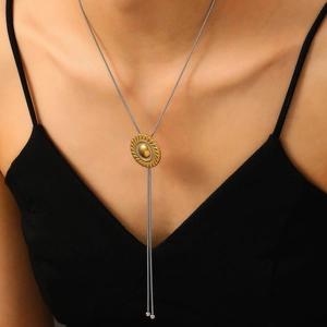 Détail d'un pendentif vintage doré sur une chaîne serpent argentée portée par un mannequin