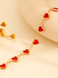 Detalle macro del colgante de corazón rojo y cadena con borlas doradas sobre fondo