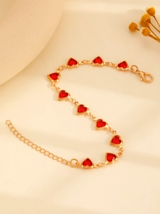 Détail du collier à maillons dorés avec neuf pierres en forme de cœur rouge et fermoir mousqueton