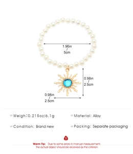 Detail of faux pearl beaded bracelet featuring golden sun charm with blue resin stone