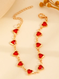 Détail d'un collier cœur doré avec pendentifs en cristal rouge et fermoir mousqueton