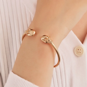 Detailansicht des goldenen Totenkopf-Manschettenarmbands am Handgelenk mit Strickpullover
